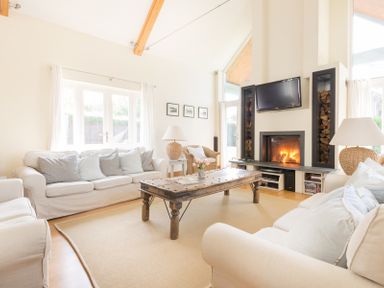 A living room with white sofas wooden coffee table fireplace and a television at Ragleighs in Daymer Bay