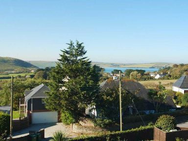 A rural area with houses trees and a body of water in the background at Ragleighs Daymer Bay