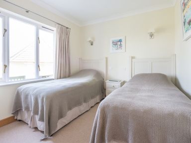 A bedroom with two single beds and a window at Ragleighs in Daymer Bay