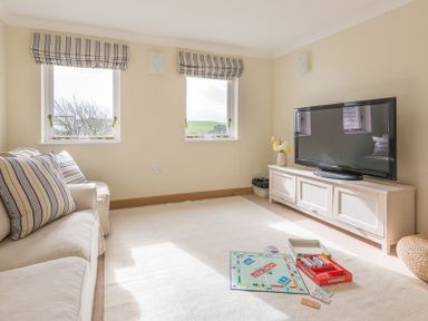 A living room with a sofa a television and a board game on the floor at Ragleighs Daymer Bay