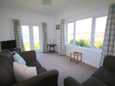 A sitting room with two brown sofas a small wooden table and a television at Gullsway September Tide in Polzeath