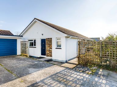 A white bungalow with a blue door and garage with trellis fencing in front at Little Sailing in Rock