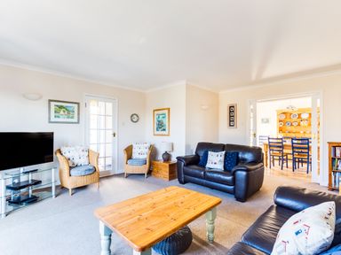 A living room with leather sofas wicker chairs a wooden coffee table and a television at Little Sailing in Rock