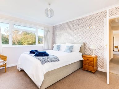 A bedroom with a bed towels on it bedside table with lamp and a window showing outdoor greenery at Little Sailing in Rock