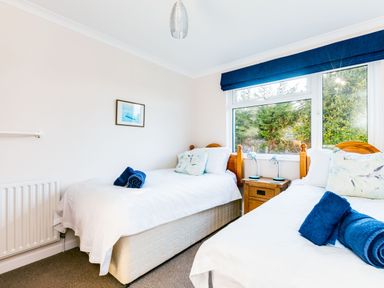 A bedroom with two single beds and a window with a blue blind at Little Sailing in Rock