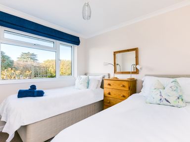 A bedroom with two single beds a wooden chest of drawers and a window with a blue valance at Little Sailing in Rock
