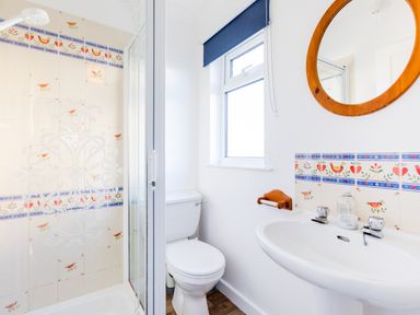 A bathroom with a toilet sink shower and round mirror at Little Sailing in Rock