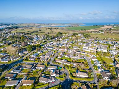 An aerial view of a residential neighborhood with houses roads and green fields near the coast at Little Sailing in Rock