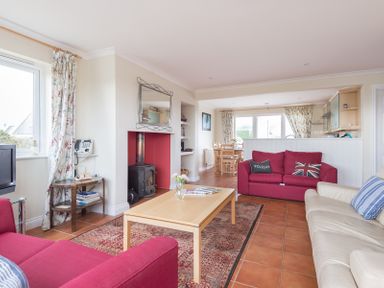A living room with two red sofas a beige sofa and a wooden coffee table at Kirra in Polzeath