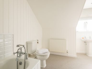 A bathroom with a bathtub a toilet with a towel on the seat a radiator and a sink at Porthilly Brook in Rock