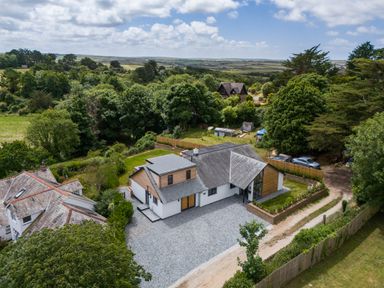 A house with a gravel driveway surrounded by trees and fields at Porthilly Brook in Rock