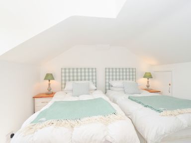 A bedroom with two beds and a lamp at Porthilly Brook in Rock