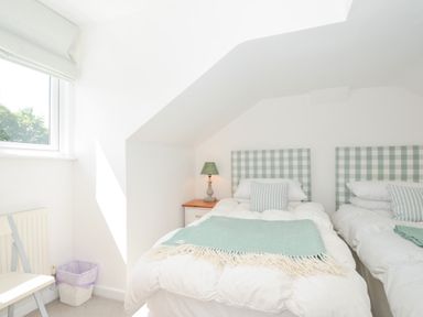 A bedroom with two beds and a lamp on a nightstand at Porthilly Brook in Rock