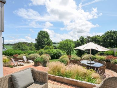A garden with a table and chairs under an umbrella at Porthilly Brook in Rock