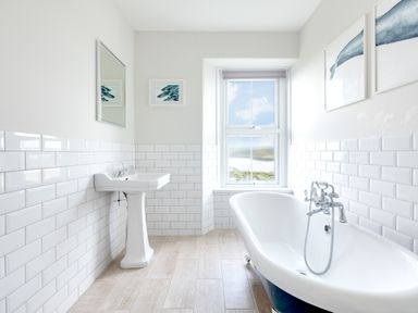 A bathroom with a pedestal sink and clawfoot bathtub near a window at Pentire View (3) in Polzeath
