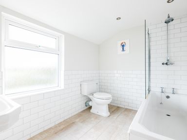 A bathroom with a toilet bathtub with shower and window at Pentire View (3) in Polzeath