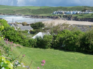 A coastal landscape with houses near a sandy beach and green hills in the background at Pentire View (3) in Polzeath