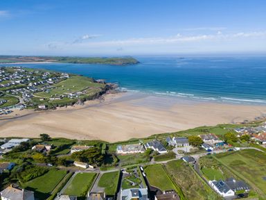A coastal village with houses green fields and a sandy beach by the sea at Treverden in Polzeath