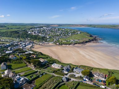An aerial view of a coastal town with a sandy beach green fields and houses at Treverden in Polzeath