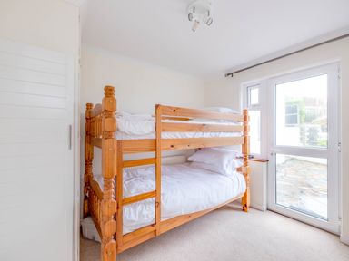 A bedroom with wooden bunk beds and a glass door leading outside at Shilling Stones Port Isaac