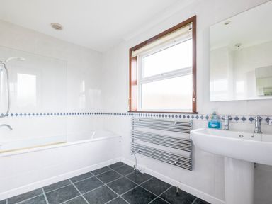 A bathroom with a bathtub shower sink window and towel radiator at Shilling Stones in Port Isaac