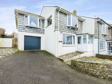 The exterior of a two-story house with a garage driveway and stone patio at Shilling Stones in Port Isaac