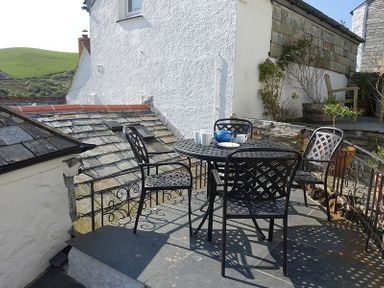 An outdoor patio with a metal table and four chairs a teapot and cups on the table at Bre Cottage Port Isaac
