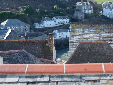 A view of rooftops with chimneys and white houses on a hillside near water at Bre Cottage in Port Isaac