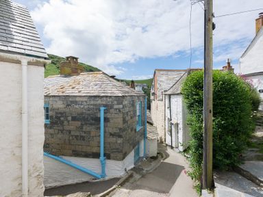 A narrow street with stone and white houses with slate roofs and blue window frames and pipes at Bre Cottage in Port Isaac