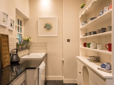 A small kitchen with a sink kettle and shelves with cups and bowls at Folly 2 in Port Isaac
