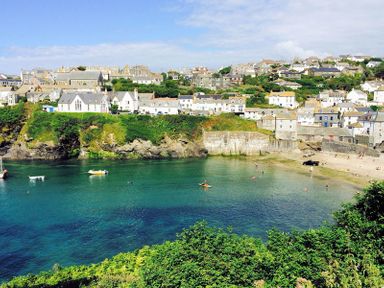 A coastal village with houses on a hill overlooking a bay with boats and a small beach at Folly 2 in Port Isaac
