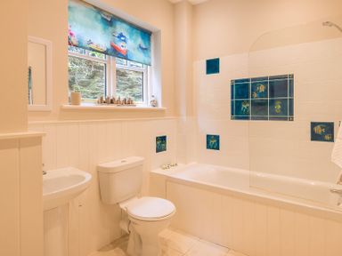 A bathroom with a toilet sink bathtub and window with a blue marine-themed blind at Folly 2 in Port Isaac