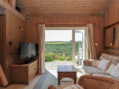 A living room with a television and sofa at Cartway Cabin in Port Isaac