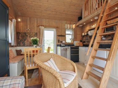 A living room with a kitchen area and stairs at Cartway Cabin in Port Isaac