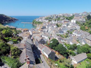 An aerial view of a coastal village with houses on a hillside and a bay with boats in the sea at Crow's Nest in Port Isaac