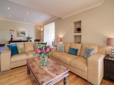 A living room with leather sofas a wooden coffee table with flowers and table lamps at Worthy House Daymer Bay