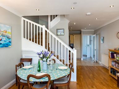 A dining area with a round table set near stairs and a bookshelf in a hallway at Lowenna Manor 4 Rock