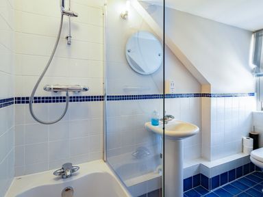 A bathroom with a bathtub shower and sink with a mirror above and toilet near a window at Lowenna Manor 4 Rock