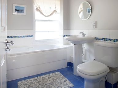 A bathroom with a bathtub sink toilet round mirror and blue tiled floor at Lowenna Manor 4 Rock