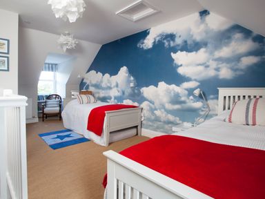 A bedroom with two beds red blankets and a cloud mural on the wall at Lowenna Manor 4 in Rock