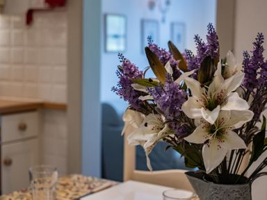 A bouquet of white and purple flowers on a table in a kitchen with white tiles and wooden countertop at April Cottage in Port Isaac