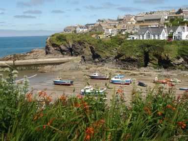 A coastal village with boats on a shore and houses on a hill in the background at April Cottage in Port Isaac