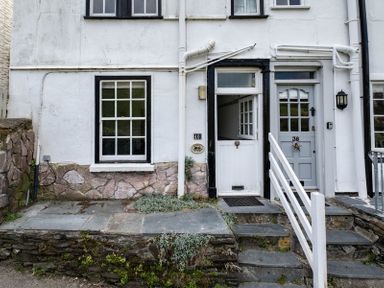 Exterior of two adjacent doors numbered 40 and 38 with stone steps white railings and a window at April Cottage in Port Isaac