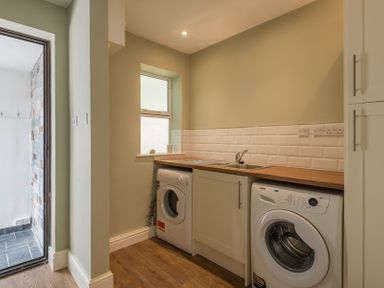 A utility room with washing machines a sink and wooden countertop at Carn Du 1 in Rock
