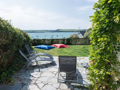 A garden patio with outdoor chairs two bean bags and a view of boats on the water at Carn Du 1 in Rock