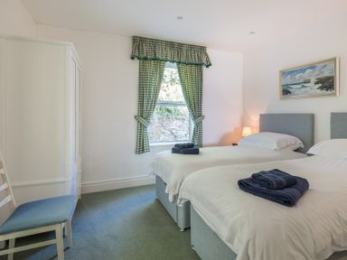 A bedroom with two single beds white furniture green checked curtains and a painting at Carn Du 1 in Rock