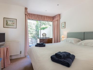 A bedroom with a bed with towels on it a chest of drawers and a window with pink curtains at Carn Du 1 in Rock