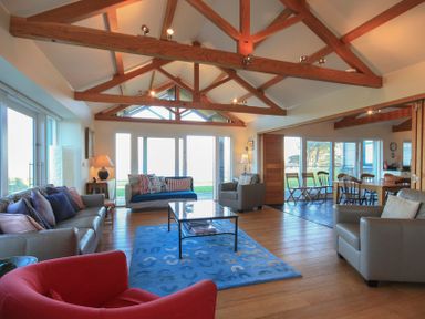 A living room with sofas chairs a coffee table and a dining table with chairs at Ossco in Polzeath