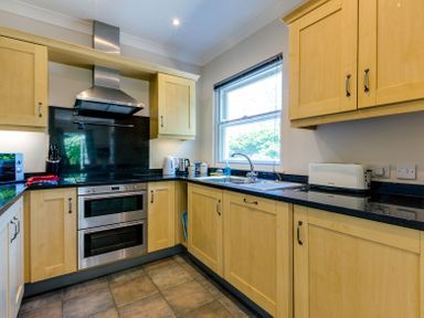 A kitchen with wooden cabinets a window a double oven a stainless steel hood a toaster and a sink at Lowenna Manor 10 Rock