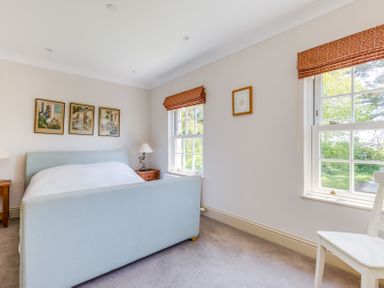 A bedroom with a bed two nightstands lamps framed pictures and two windows at Lowenna Manor 10 Rock